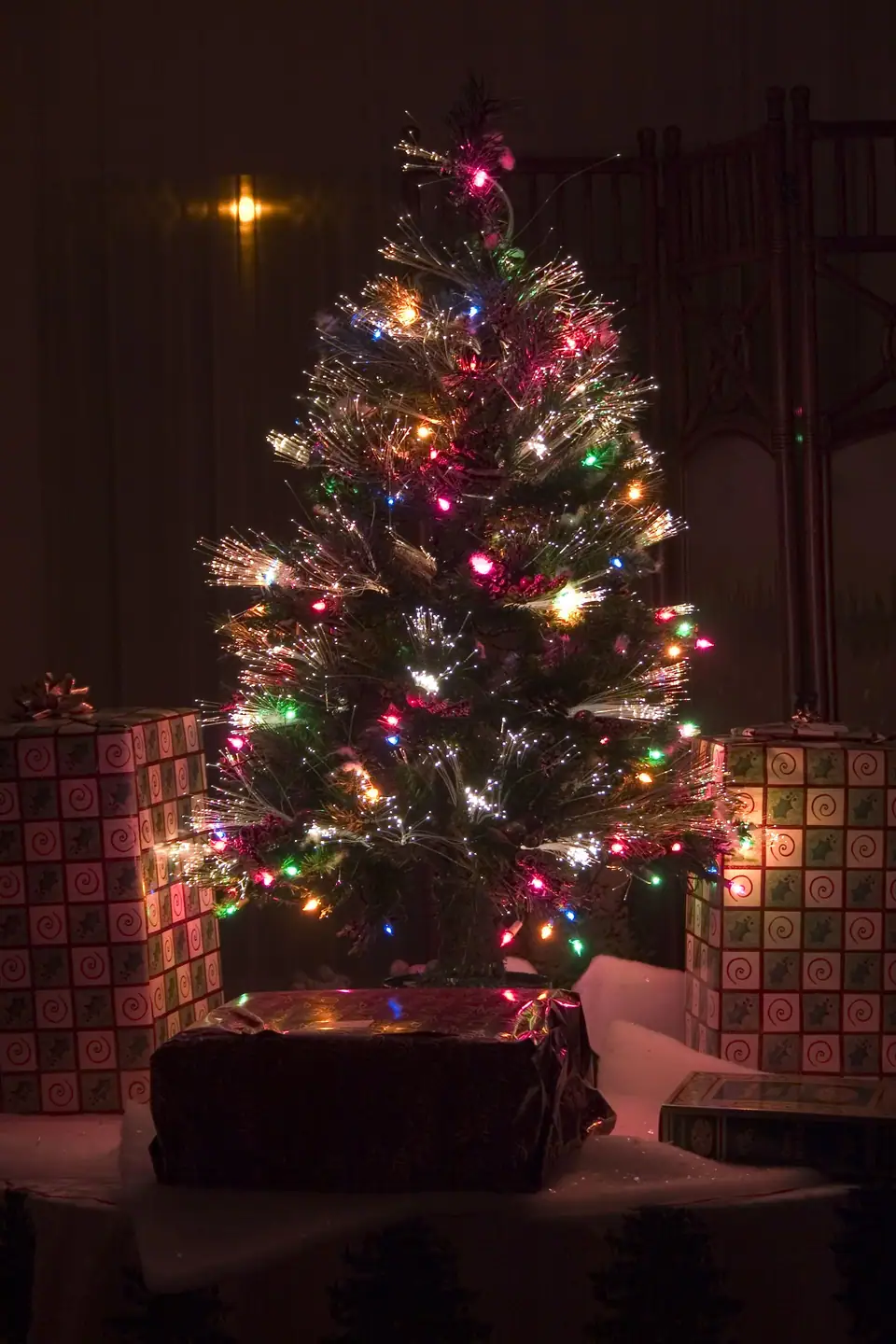 An artificial Christmas tree lit with fiber optic strands and string lights
